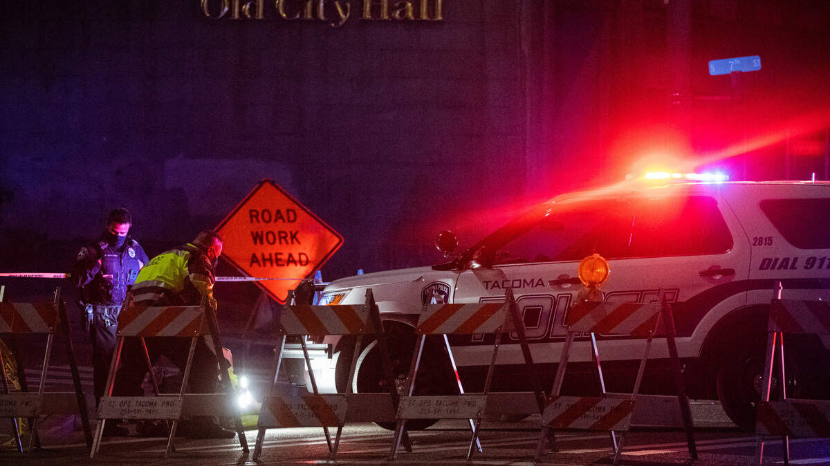 Police investigate a Tacoma police car near South 9th Street and Pacific Avenue where earlier a Tacoma police car ran through a crowd of people at the scene of cars doing burnouts in Tacoma, Wash., on Saturday, Jan. 23, 2021.