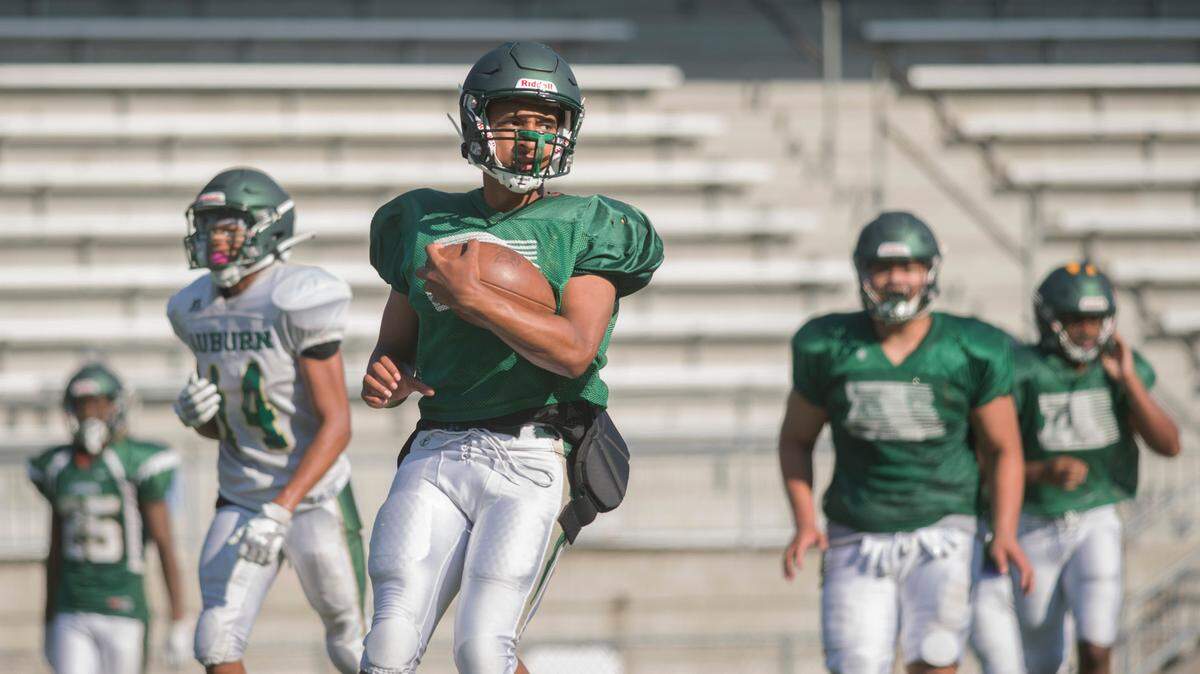 Auburn High School quarterback Amari Goodfellow (center) runs with the ball during a scrimmage period at practice on Tuesday, Aug. 23, 2022 in Auburn, Wash.