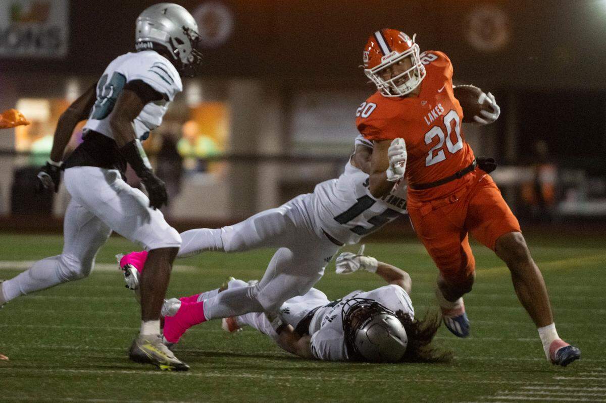 Lakes running back Leo Pulalasi turns the corner as he is tackled by Spanaway Lake Nakobe Romeo during the first quarter of a 3A PCL game on Monday, Oct. 17, 2022, at Harry E. Lang Stadium in Lakewood, Wash.