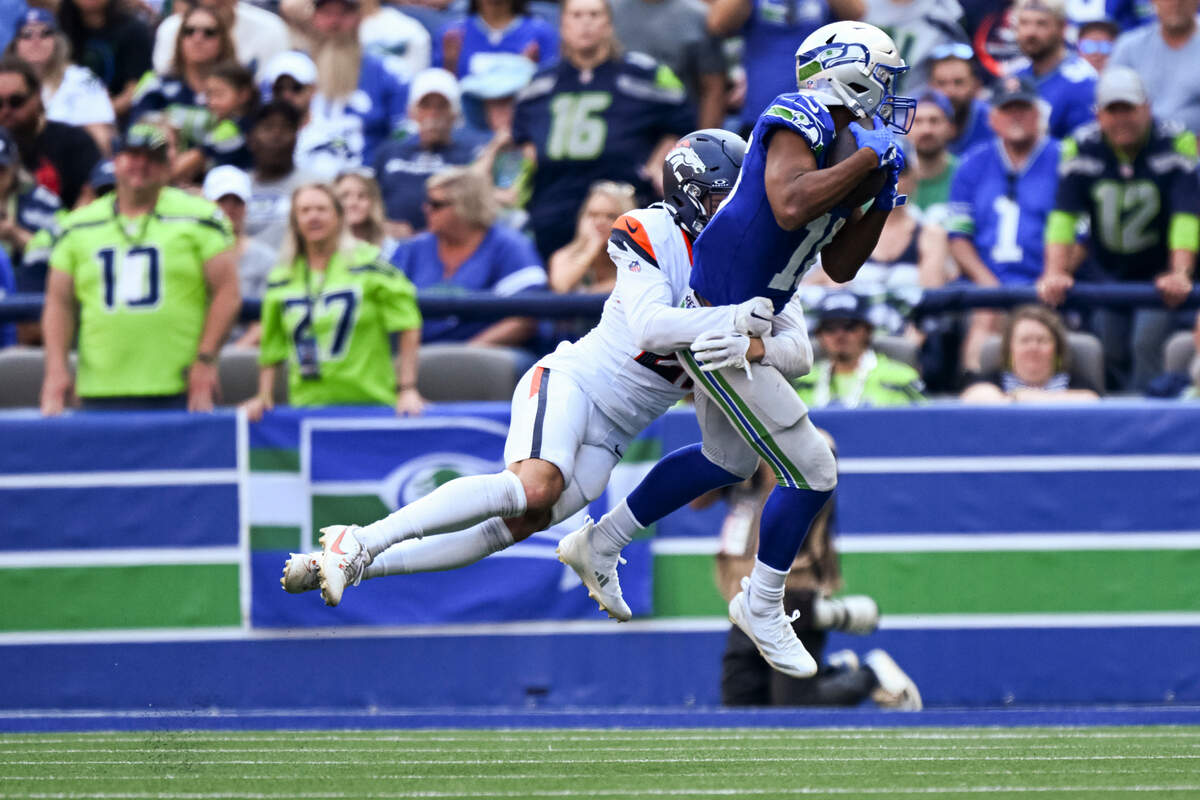 Seahawks wide receiver Tyler Lockett (16) goes up for the game-clinching catch against Denver Broncos cornerback Riley Moss (21) during the fourth quarter of the game at Lumen Field, on Sunday, Sept. 8, 2024, in Seattle.
