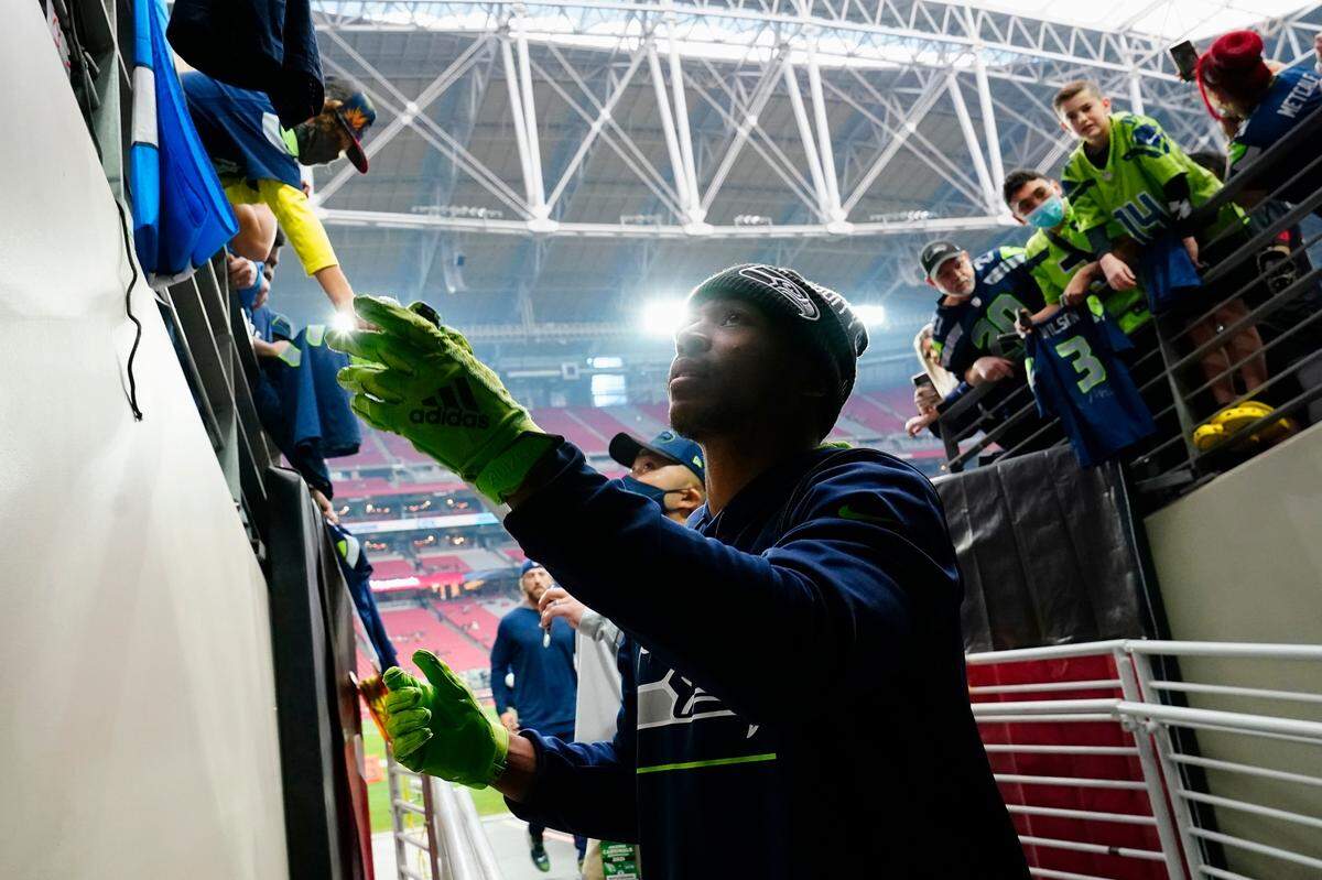 Seattle Seahawks wide receiver Tyler Lockett signs autographs for fans prior to an NFL football game against the Arizona Cardinals Sunday, Jan. 9, 2022, in Glendale, Ariz. (AP Photo/Ralph Freso)