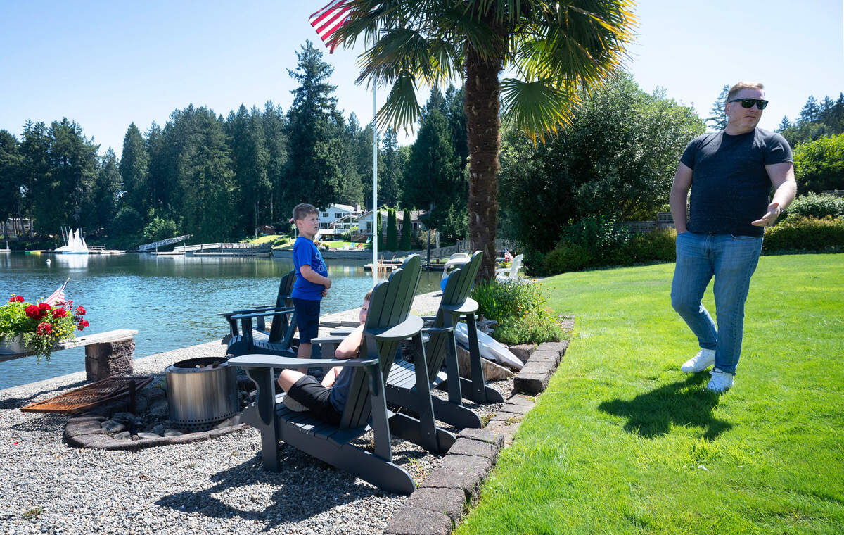 Chris Teitzel with his sons, Caleb Teitzel, 9, and Evan Teitzel, 7, at their family’s home on Wollochet Bay in Gig Harbor, Washington, on Friday, July 28, 2023. Teitzel said a lack of enforcement on the waterway has allowed problems to escalate, including non-registered anchoring causing difficult navigation and dangerous encounters between boaters and kayakers.