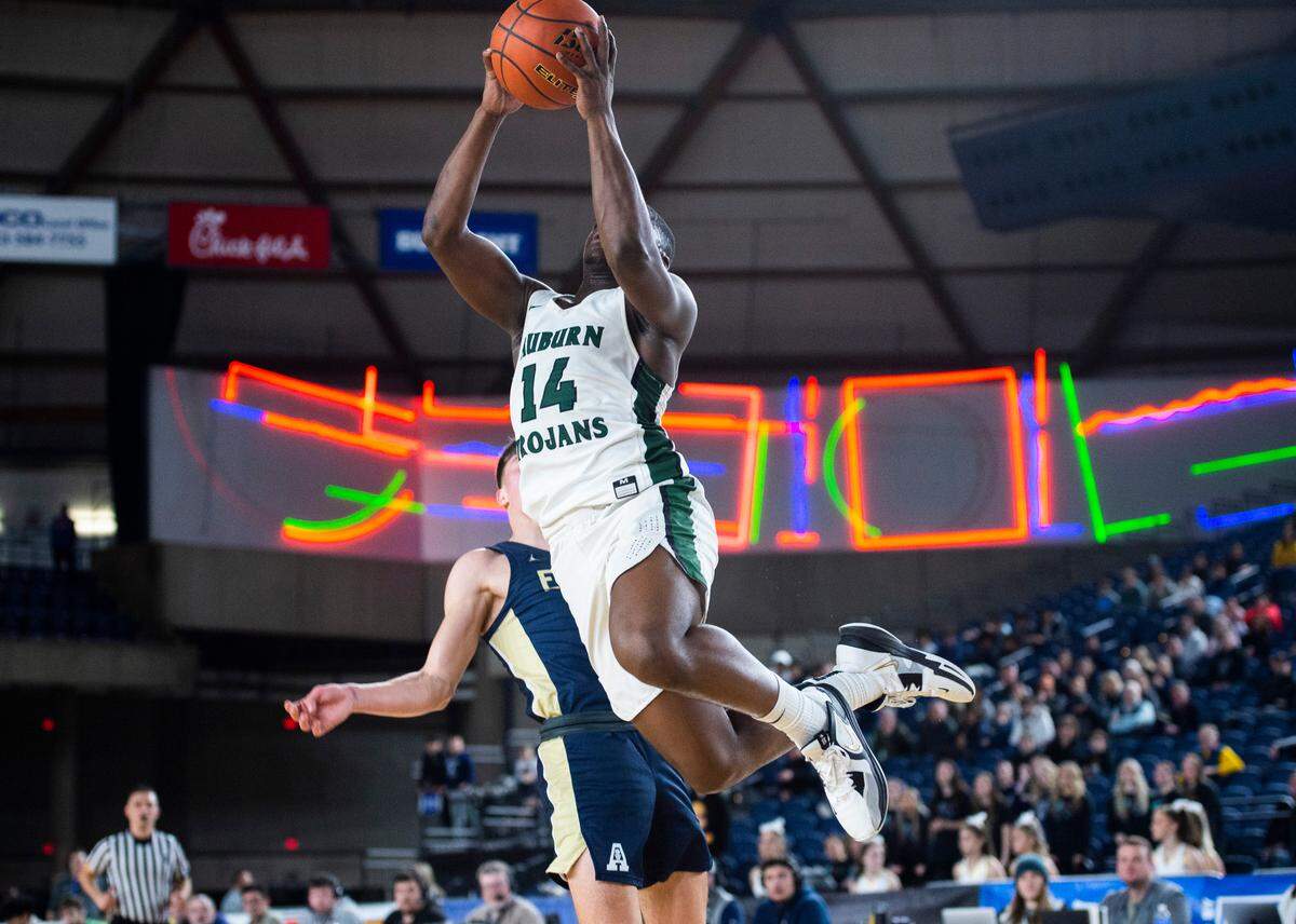 Auburn guard Luvens Valcin (14) takes a jump shot and lands on Arlington forward Jacoby Falor (5) during an opening round game at the WIAA state basketball tournament in the Tacoma Dome in Tacoma, Washington, on Wednesday, March 1, 2023. Auburn won the game 52-41.