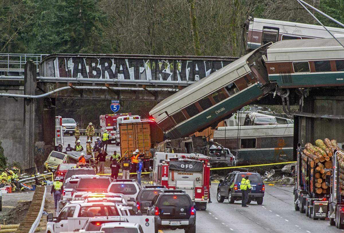 Several cars from an Amtrak passenger train dangle from an overpass onto the lanes of southbound Interstate Five near DuPont, December 18, 2017.