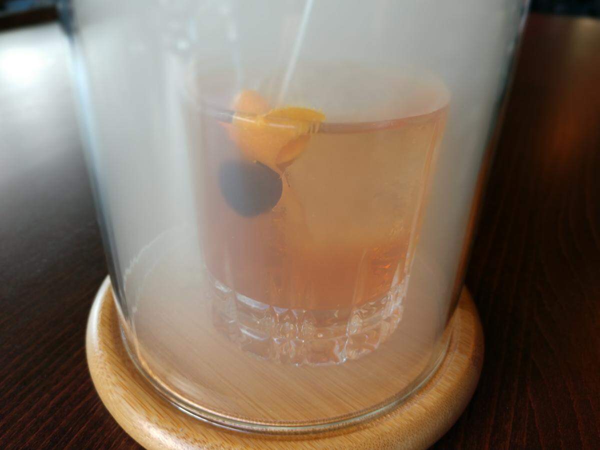 A glass dome encases smoke that flavors an old fashioned cocktail, at Glow Martini Lounge in Bonney Lake.