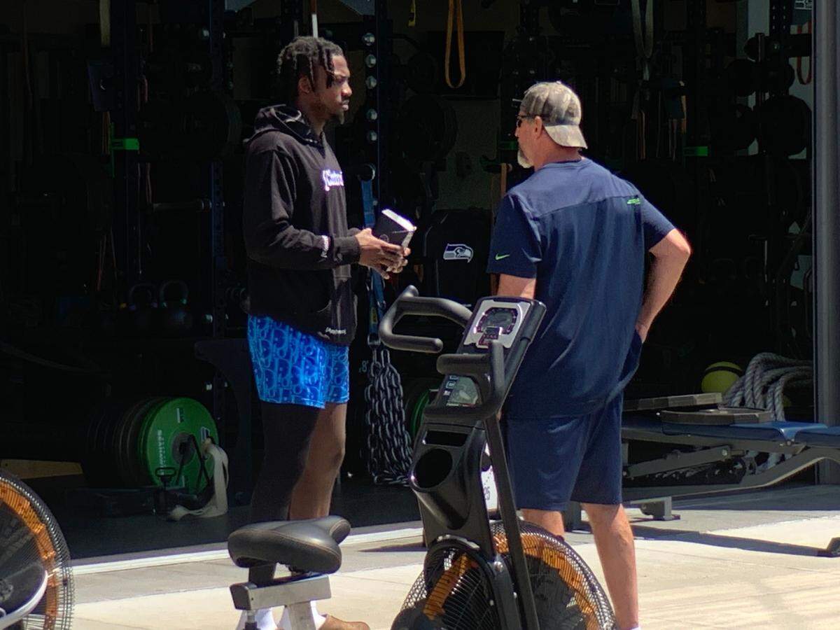 Tariq Woolen talks with a Seahawks staff member during the fifth organized team activities practice for the team June 1, 2023, at the Virginia Mason Athletic Center in Renton. Woolen had arthroscopic knee surgery in mid-May.
