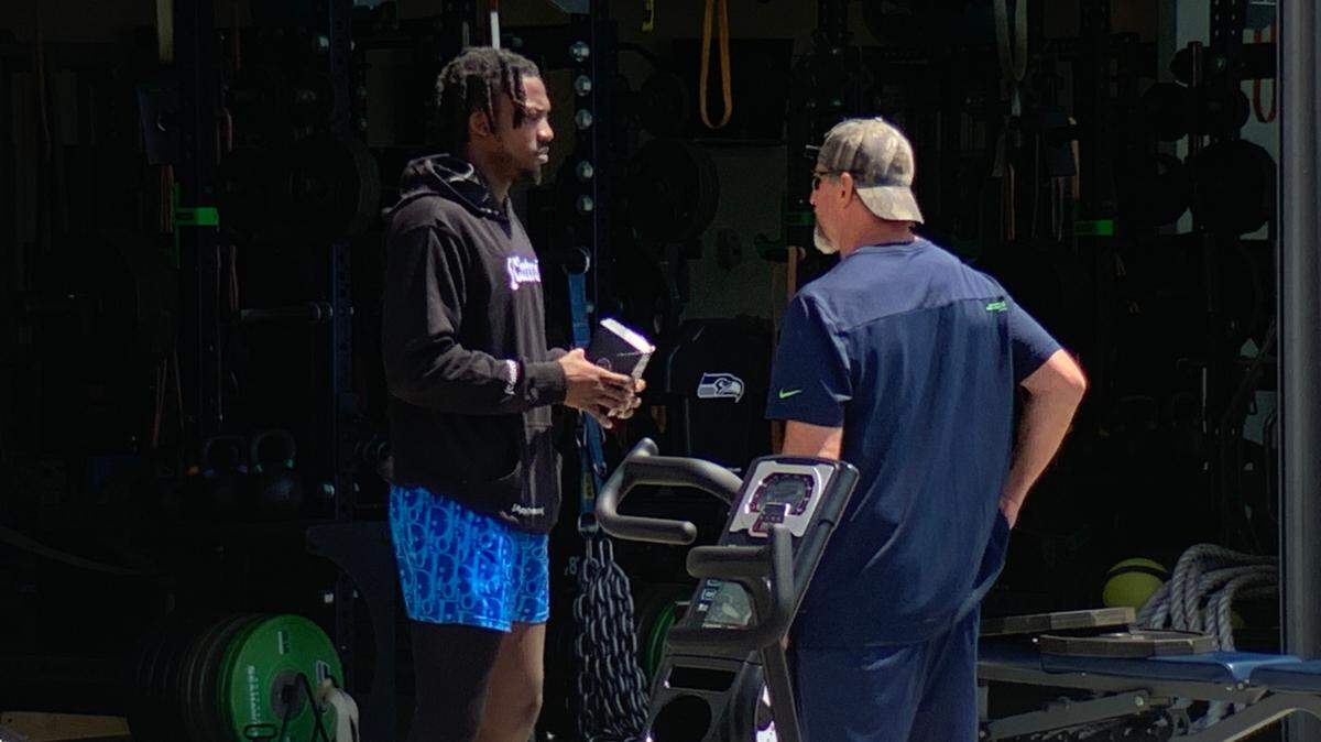 Tariq Woolen talks with a Seahawks staff member during the fifth organized team activities practice for the team June 1, 2023, at the Virginia Mason Athletic Center in Renton. Woolen had arthroscopic knee surgery in mid-May.