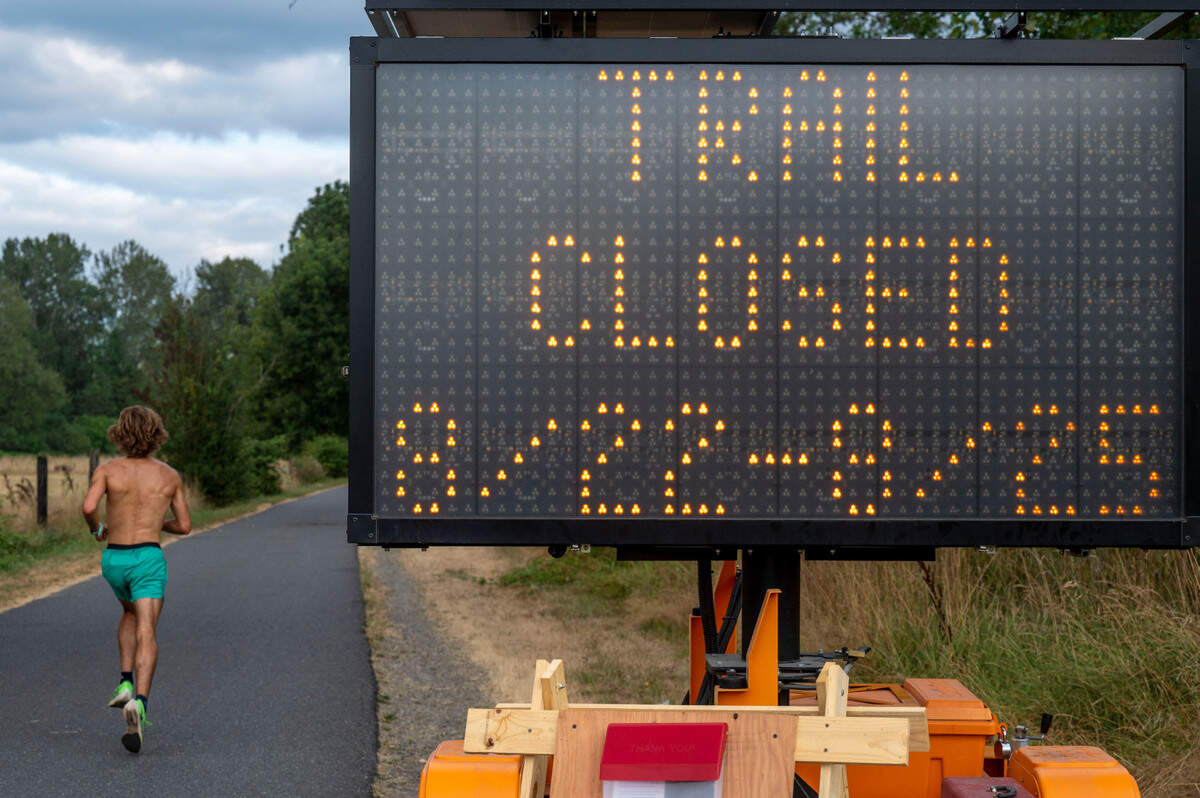 A man runs past a sign along the Foothills National Recreation Trail on Saturday, Aug. 20, 2022, in Orting. The sign notifies patrons of the 21-mile-long path that a half-mile of the trail will be closed from 7:30 a.m. to 4:30 p.m. on Aug. 22 through Aug. 25. The section closed is just south of Orting where crews will be repairing a levee along the Carbon River.