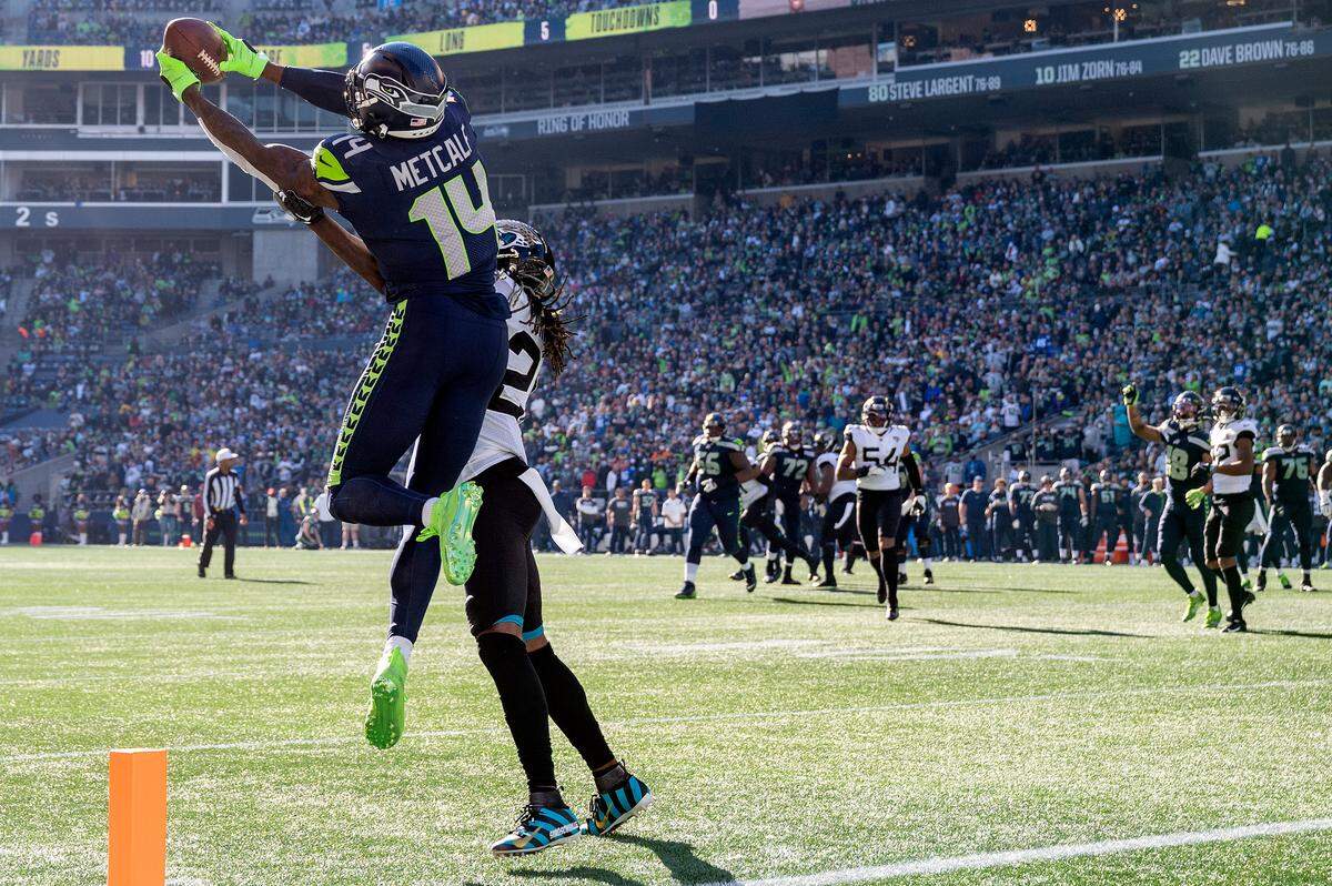 Seattle Seahawks wide receiver DK Metcalf (14) catches pass from quarterback Geno Smith (7) as Jacksonville Jaguars cornerback Shaquill Griffin (26) defends during the second quarter of an NFL game on Sunday at Lumen Field in Seattle. Metcalf would score on the play.