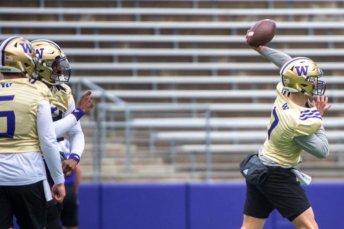 Washington’s Sam Huard (7) winds up to throw a pass as fellow quarterbacks Dylan Morris (5) and Michael Penix, Jr. (9) look on during drills at spring practice on Wednesday, March 30, 2022, at Husky Stadium in Seattle, Wash.