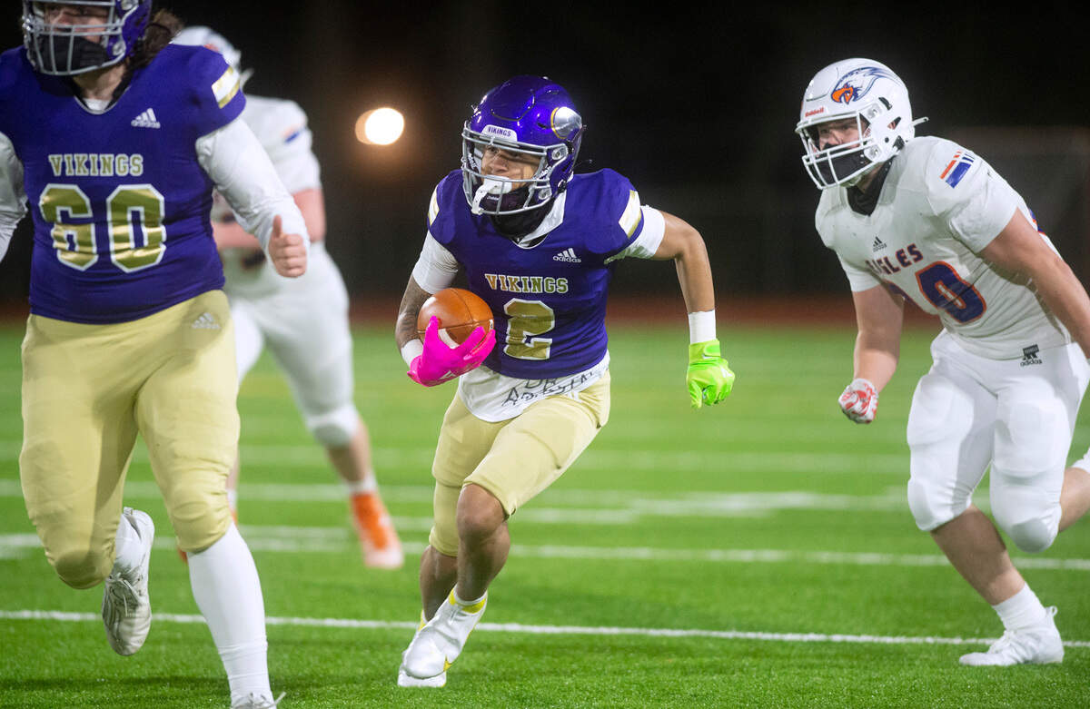 Puyallup wide receiver Jordan Dwyer heads up field in front of Graham-Kapowsin defensive end Caleb Trent during Thursday night’s football game at Sparks Stadium in Puyallup, Washington, on March 11, 2021.