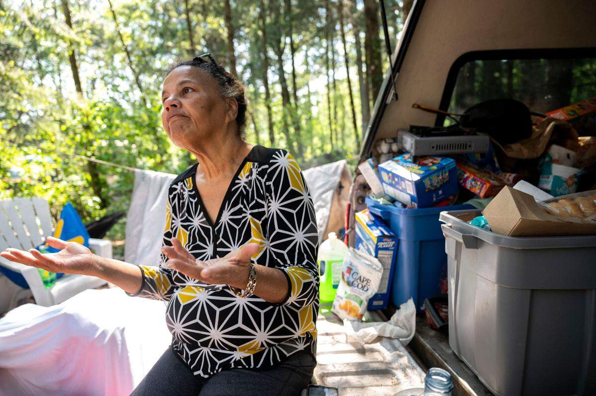 Bouviea Aaron, 65, sits on the back of her truck, where she also sleeps, while talking about some of the issues that persist at the homeless camp she lives in on the 9700 block of Steele Street South on Thursday, May 25, 2023, in Tacoma. Known as “The Jungle,” the camp is home to roughly 30-40 people at any given time. Aaron has lived there for the past three months while she attempts to sort out a permanent living situation.