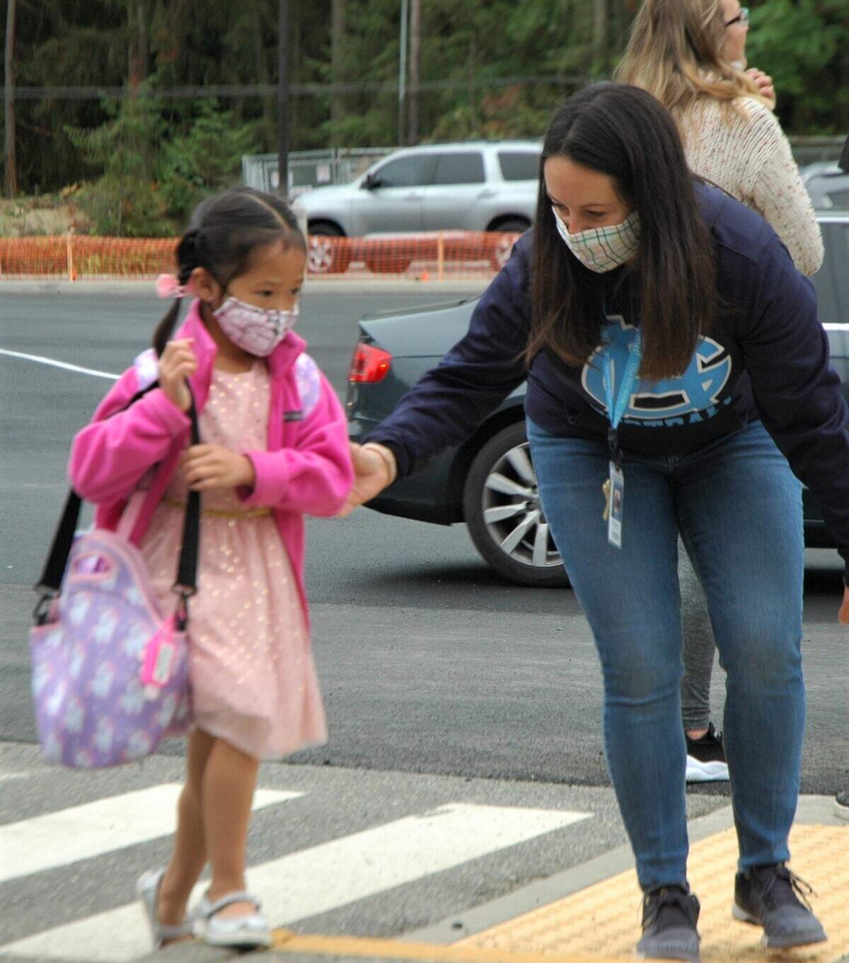 New kindergartner Leana Tan, 5, dressed in her best, is guided over a speed bump by an Artondale counselor on the first day of school.