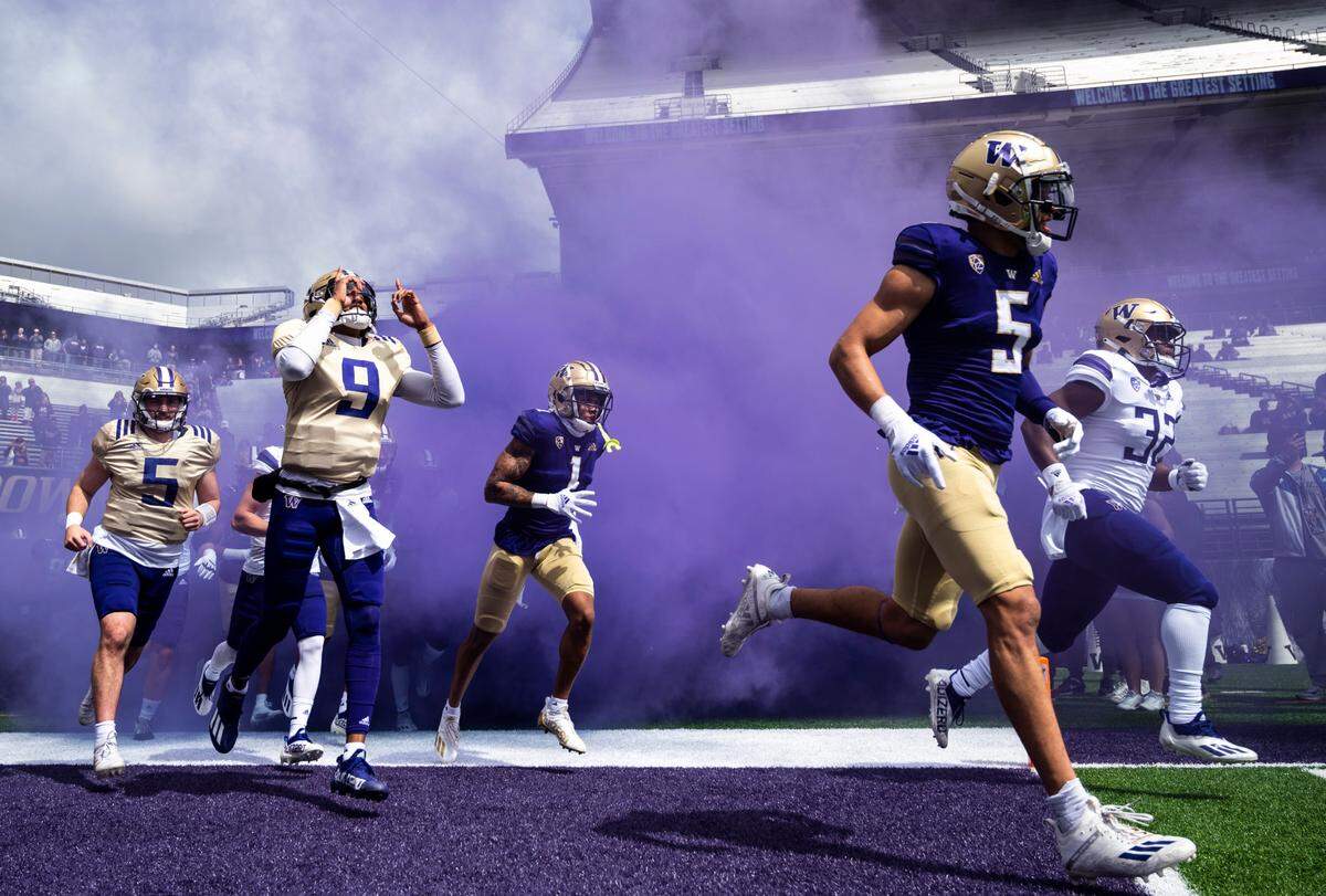 University of Washington Huskies quarterback Michael Penix Jr. (9) points to the sky as he runs onto the field with quarterback Dylan Morris (5), cornerback Jordan Perryman (1) and safety Alex Cook (5) at the start of the spring game at Husky Stadium in Seattle, Wash. on Saturday, April 30, 2022.