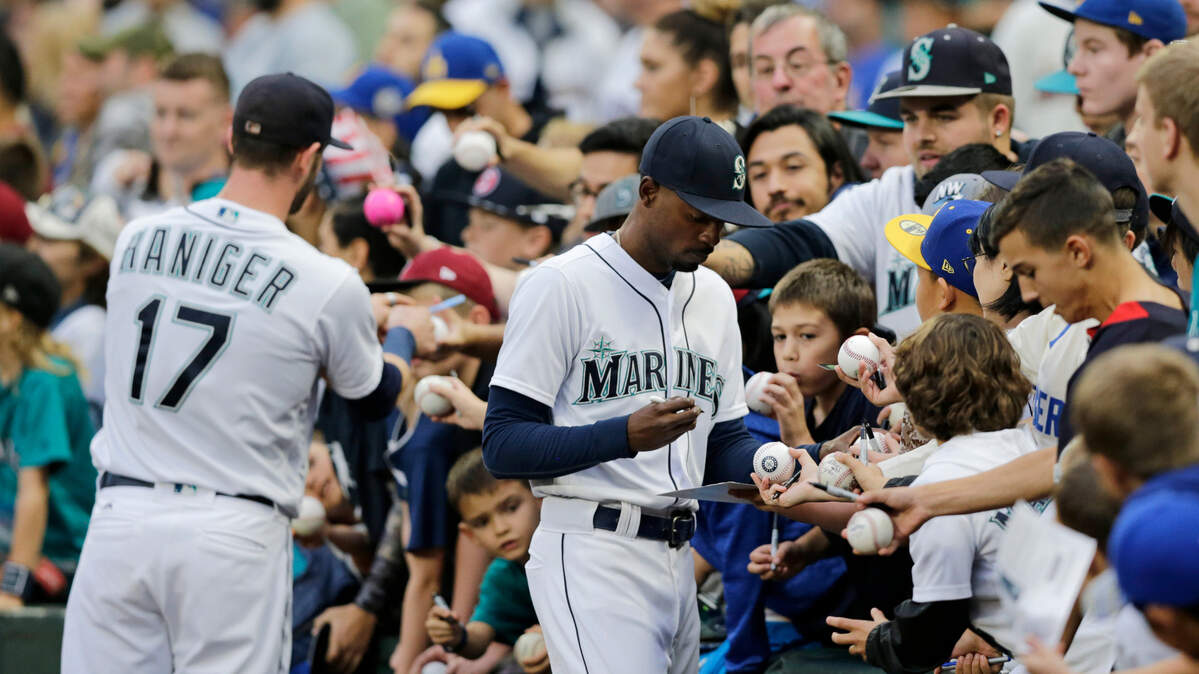 Seattle Mariners’ Dee Gordon, right, and Mitch Haniger sign autographs before a baseball game against the Texas Rangers, Saturday, Sept. 29, 2018, in Seattle. (AP Photo/John Froschauer)