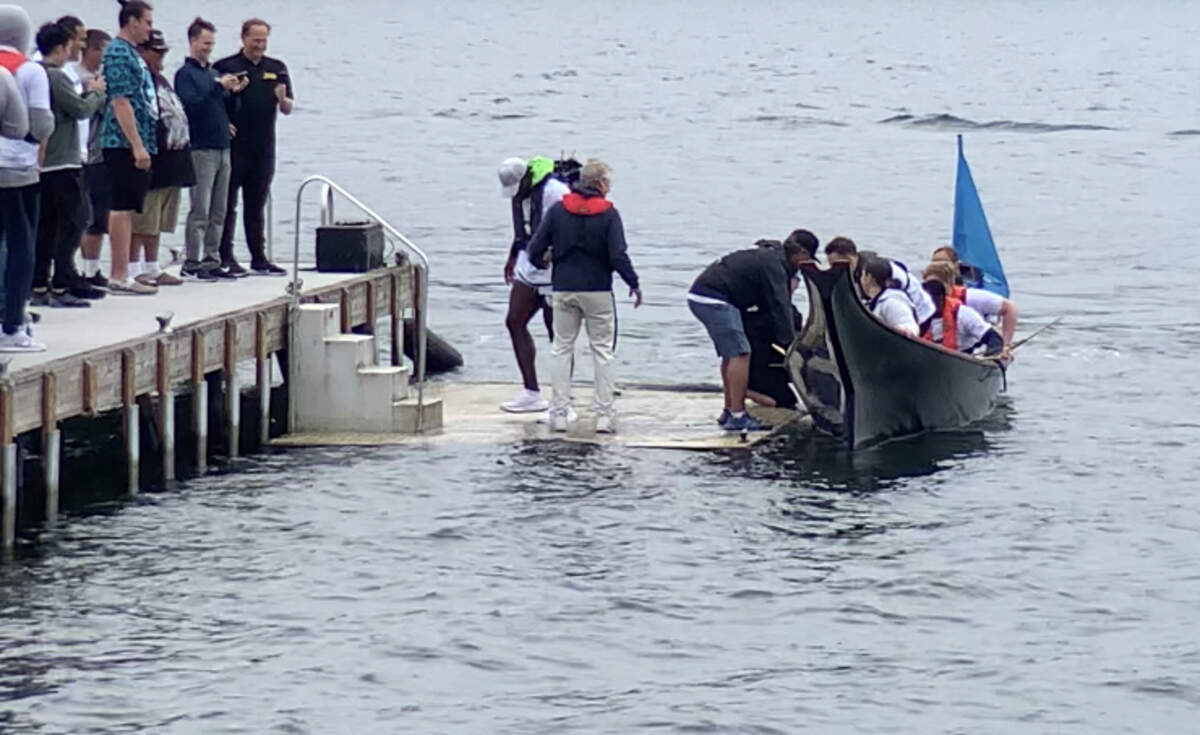 Coach Pete Carroll (in blue) greets linebacker Derick Hall back to the dock outside team headquarters in Renton. Carroll surprised Seahawks rookies with a canoe ride with the Muckleshoot Indian Tribe on Lake Washington June 13, 2023.