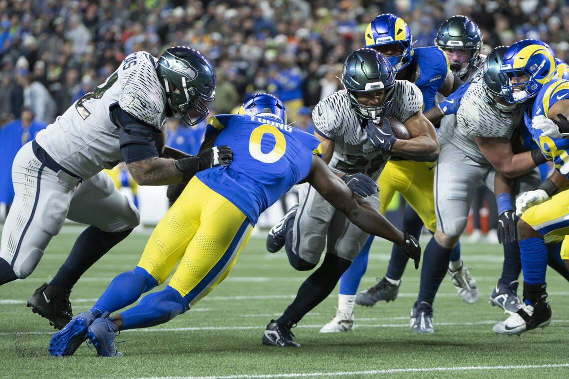 Seattle Seahawks running back Zach Charbonnet (26) carries the ball as Los Angeles Rams defenders close in during overtime at Lumen Field, on Thursday, Dec. 18, 2025, in Seattle.