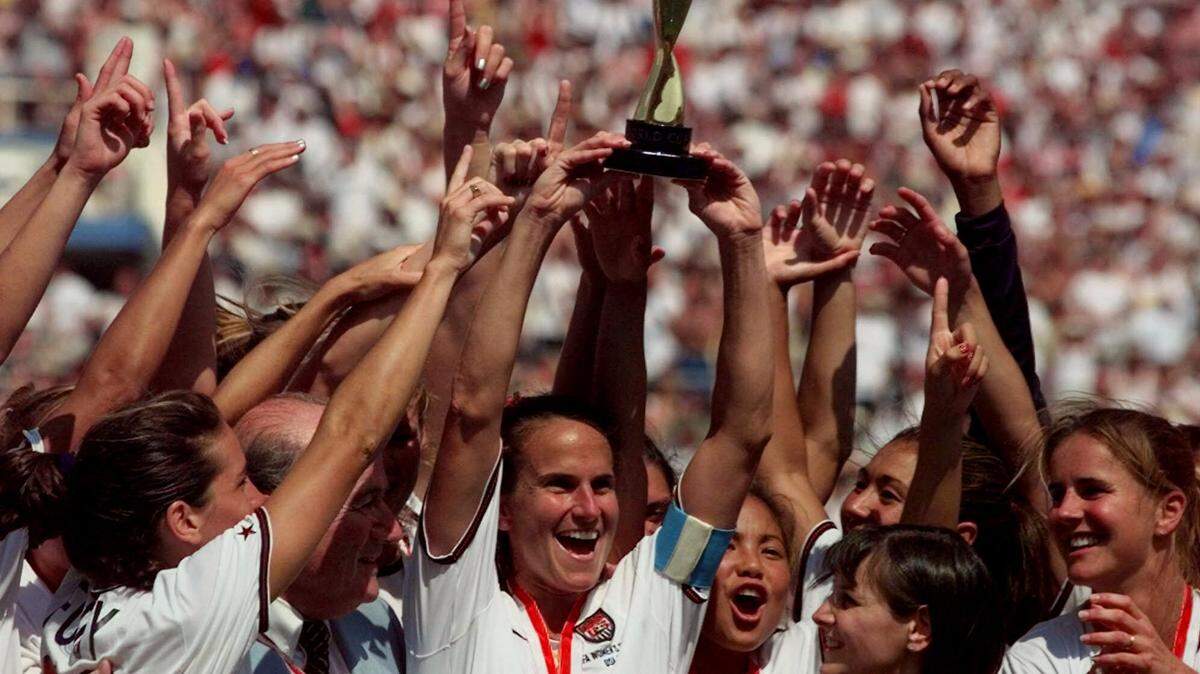 The United States soccer team captain Carla Overbeck, center, the U.S. team and FIFA President Sepp Blatter, left of Overbeck, celebrate with the trophy after defeating China in a 5-4 overtime penalty shootout during the Women’s World Cup Final at the Rose Bowl in Pasadena, Calif., Saturday, July 10, 1999. The U.S. beat China 5-4 on penalty kicks after 0-0 tie. (AP Photo/Michael Caulfield)