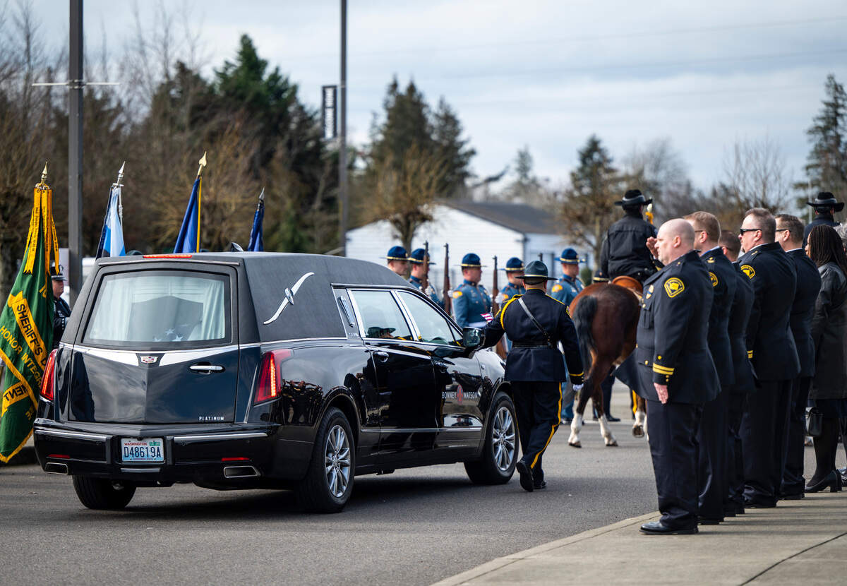 Officers walk alongside a hearse carrying Jay Miller, a former corrections officer at the Washington Corrections Center For Women, during a procession in his honor on the way to his memorial service at the Church for All Nations in Parkland, Wash. Feb. 22, 2023. Miller worked for the Department of Corrections for 30 years and passed away at the age of 56, from COVID-19 complications.