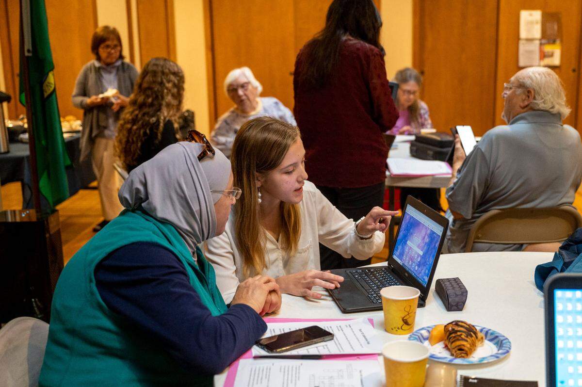 Fife High School sophomore Marguerite Schoenfeldt works with a woman on tips to use her laptop during a free workshop hosted by the school’s FBLA program to teach seniors how to navigate technology on Friday, Oct. 21, 2022, at the Milton Activity Center in Milton, Wash.