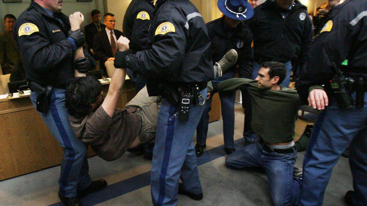 A group of protesters are stopped at the Senate Ways & Means hearing in Olympia, Wa., on Tuesday, Nov. 29, 2011. Former Way and Means chair Ed Murray asked for the protestors to be quiet, offering to hear them during the meeting process, but ordered their removal after they didn’t comply. (AP Photo/The Olympian, Steve Bloom)