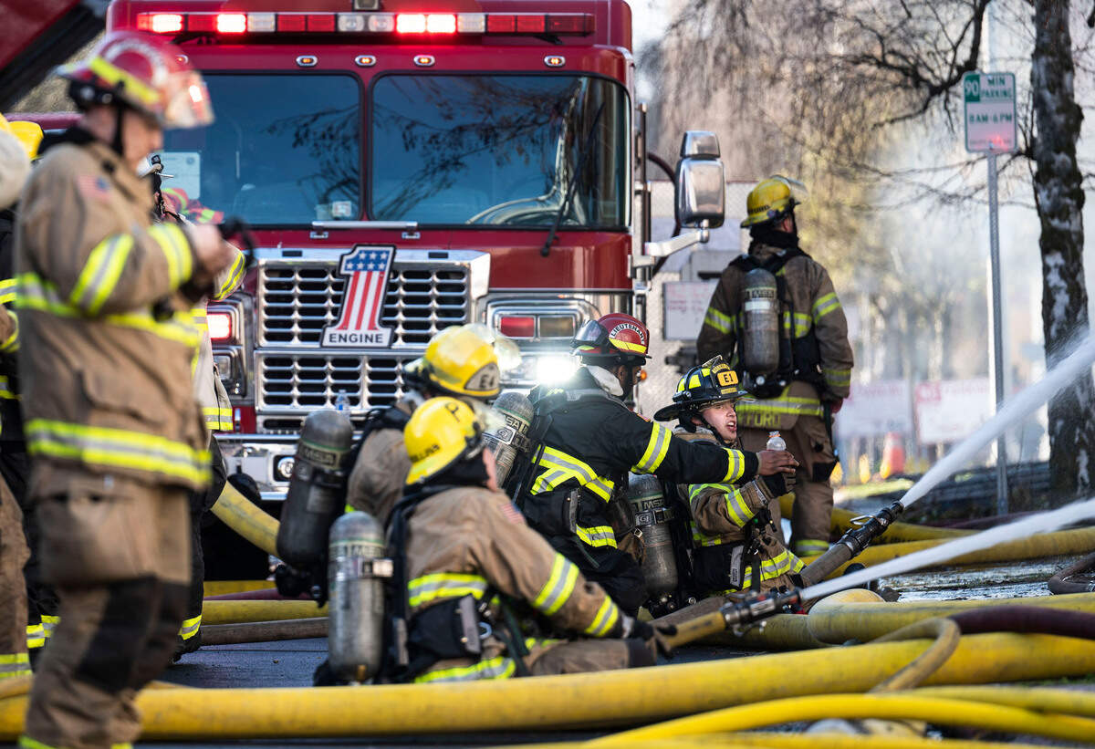 A Tacoma firefighter hands his crew member a drink while fighting a large commercial building fire at the 700 block of Fawcett Avenue in Tacoma, Wash. on March 21, 2023. Tacoma Fire Department spokesperson Joe Meinecke said no injuries have been reported, but crews aren’t sure whether anyone was inside when the fire started. He said the building is supposed to be vacant.