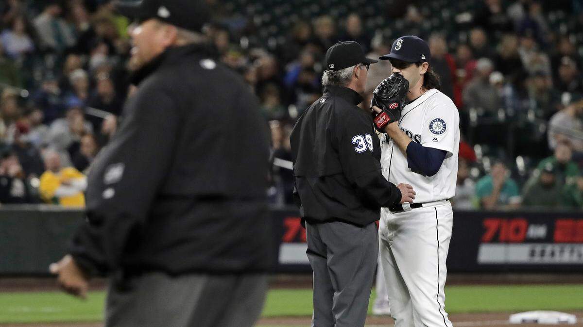 Second base umpire Paul Nauert (39) talks with Seattle Mariners pitcher Cory Gearrin, right, after officials reviewed Gearrin’s pitching motion as he warmed up after coming in in relief during the seventh inning of a baseball game against the Oakland Athletics, Monday, May 13, 2019, in Seattle.