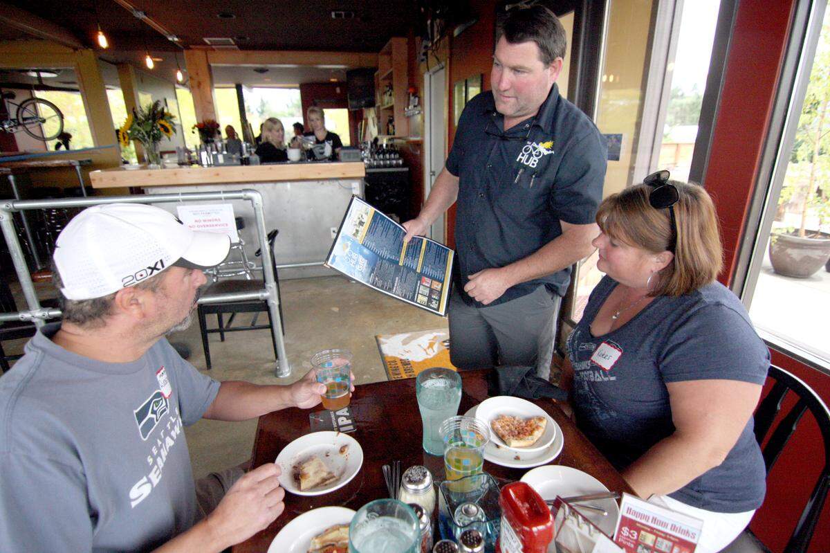 Pat Nagle helps customers Rudy Nieves and his wife Kate Healy-Nieves at a new location of The Hub at the Tacoma Narrows Airport in 2015. LEE GILES III/Staff photographer