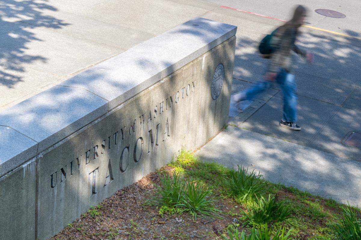 A person walks past a University of Washington Tacoma sign on Wednesday, April 23, 2025, in Tacoma. Immigration and Customs Enforcement has recently changed the status of student visas in Washington state, including recent UW Tacoma grads.
