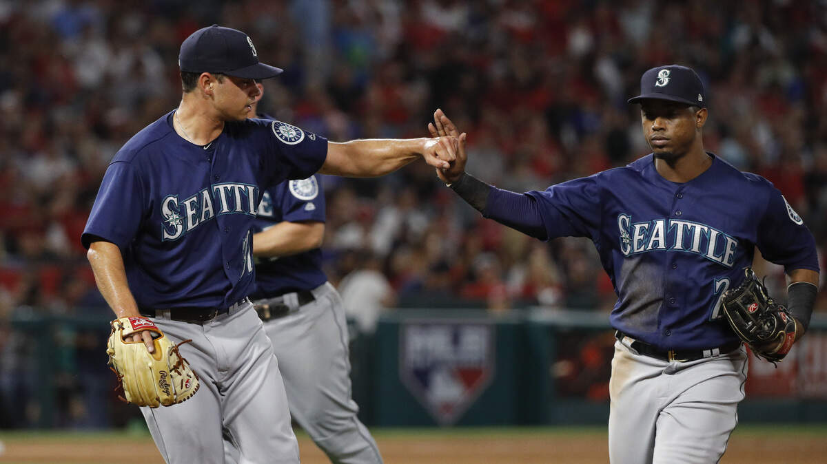Seattle Mariners starting pitcher Marco Gonzales, left, greets Jean Segura with a fist bump as they walk off the field after the sixth inning of a baseball game against the Los Angeles Angels, Wednesday, July 11, 2018, in Anaheim, Calif. (AP Photo/Jae C. Hong)