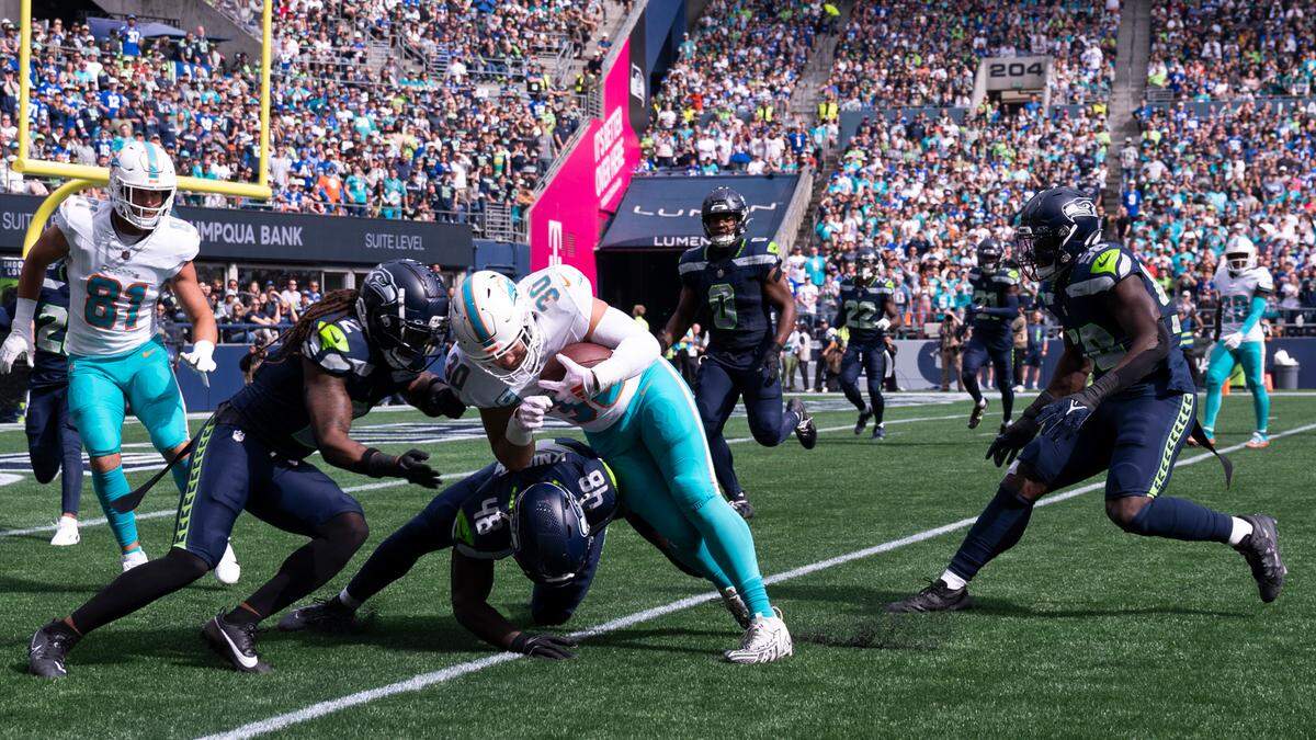 Miami Dolphins fullback Alec Ingold (30) is hit by Seattle Seahawks linebacker Tyrice Knight (48) and safety Rayshawn Jenkins (2) during the first quarter of the game at Lumen Field, on Sunday, Sept. 22, 2024, in Seattle, Wash.