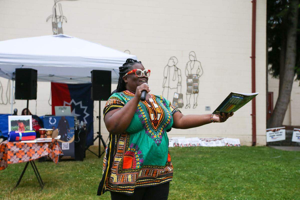 Puyallup resident Davida Sharpe-Haygood prepares to give a Black Panther coloring book to a raffle winner Saturday, June 10, 2023 at Grayland Park. A group of community members in Puyallup celebrated Juneteenth that day.