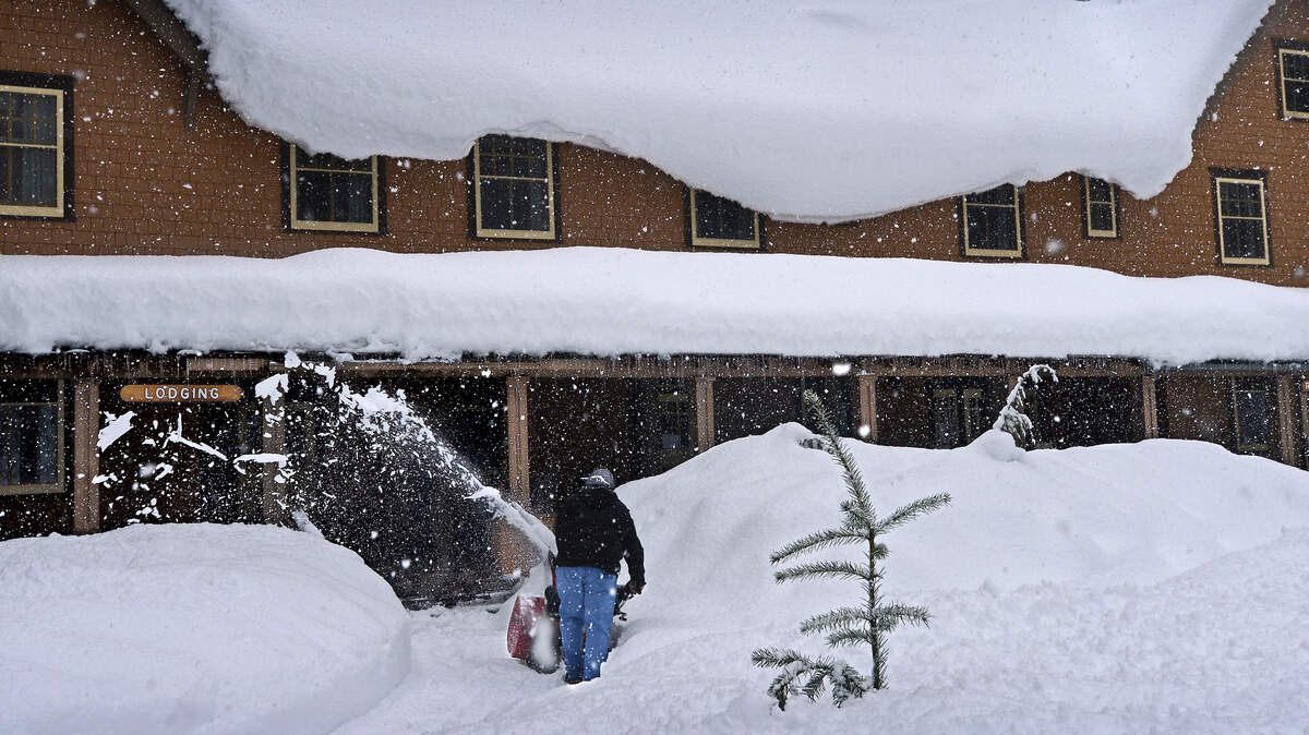 A lone worker tries to keep up with the snow in front of the National Park Inn in Longmire at Mount Rainier National Park in 2014.
