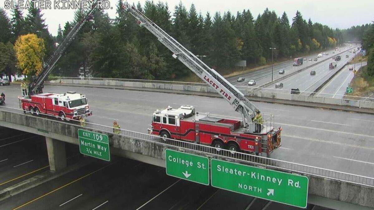 Lacey firefighters set up on an Interstate 5 overpass as a procession for Washington State Patrol trooper Eric Gunderson, who died Sunday, passes below.