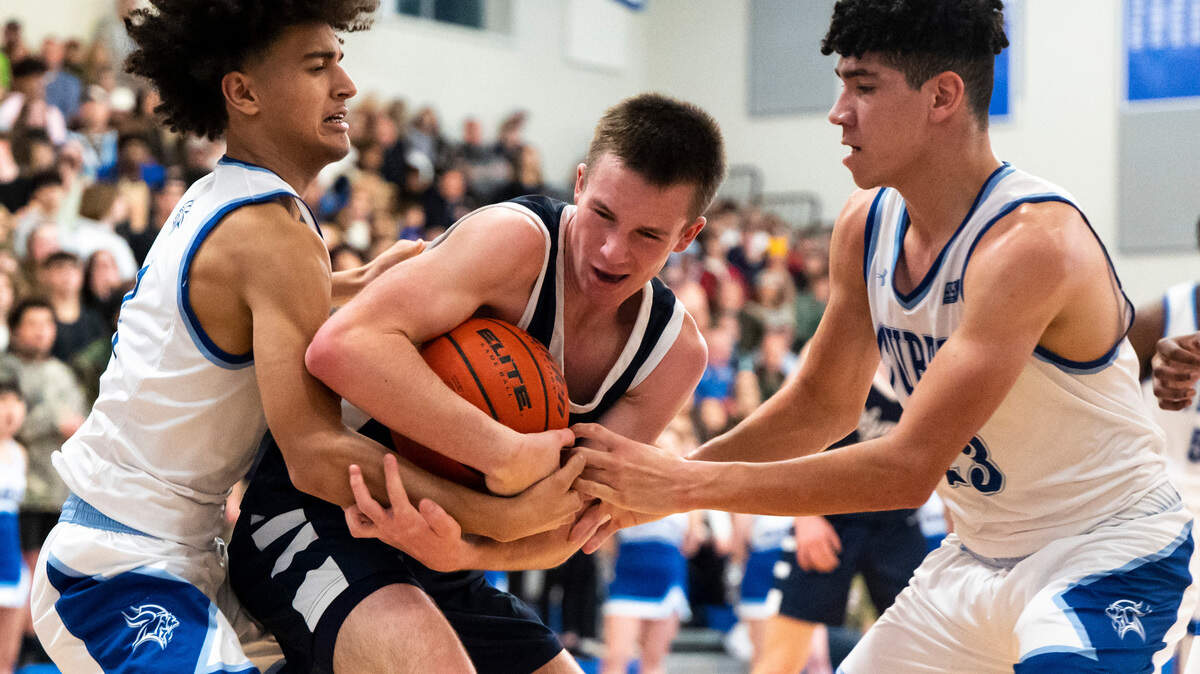 Olympia’s guard Matt Lindblom (4) wrestles for control of the ball against Curtis’s guard Bilal El Ghalemi (2) and Curtis’s forward Xavier Ahrens (23) during a basketball game at Curtis High School in University Place, Wash. on Jan. 7, 2023. Olympia defeated Curtis 72-60.