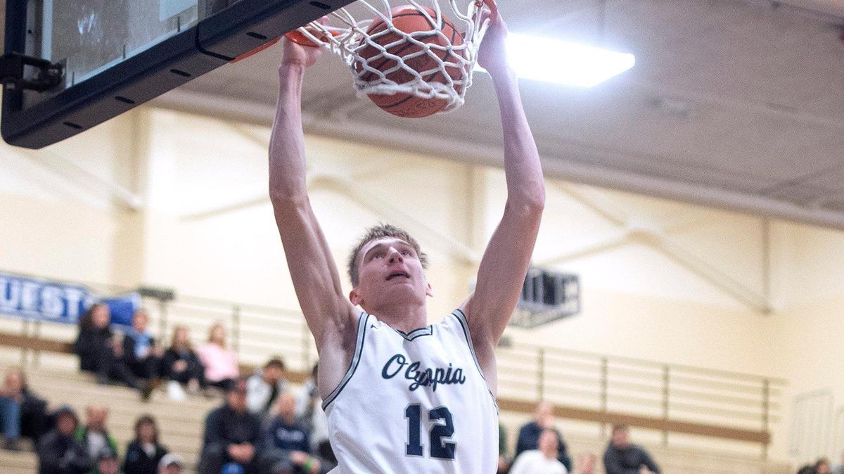 Olympia’s Jackson Grant throws down a dunk in front of Puyallup defender Luke Holcomb during Saturday night’s SPSL 4A boys basketball game at Olympia High School on Jan. 4, 2020.