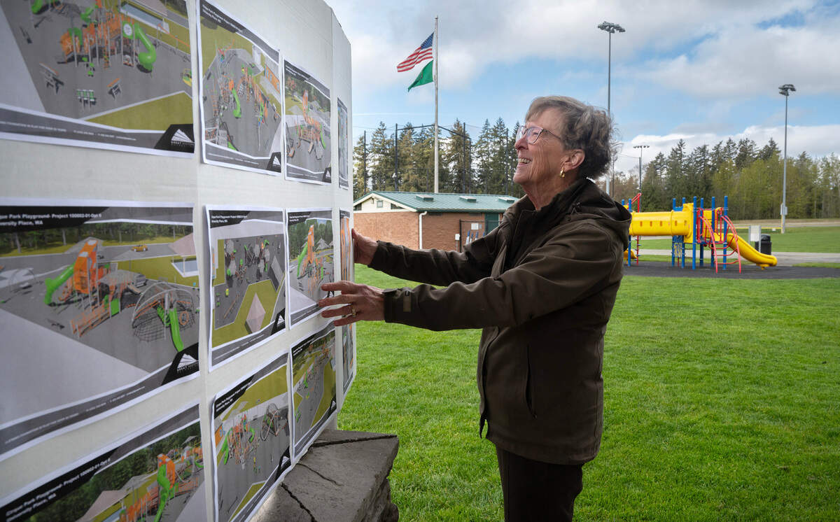 Claudia Ellesworth of the University Place Parks & Recreation Foundation looks over a display of and artist rendering showing the new disability-accessible inclusive playground plans during groundbreaking ceremonies at Cirque Park in University Place, Washington, on Friday, April 12, 2024.
