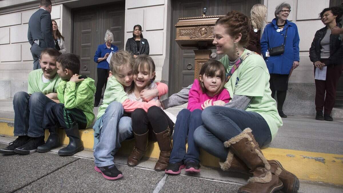 Marchel Hanna (left) of Ellensburg gives a hug to Ellen Love of Yakima as they wait with their siblings for the start of a foster care rally in Olympia in 2017. The Love and Hanna families - including mom Jessica Hanna (right) - both serve as foster families. Therapeutic group homes are another piece of Washington’s foster-care puzzle, and they’re underfunded.