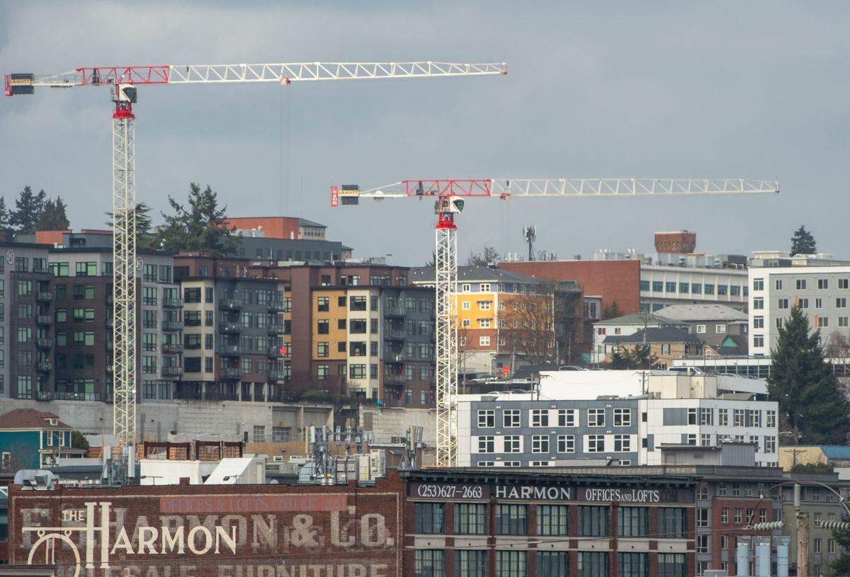 A pair of cranes stand above an apartment building just beginning construction while surrounded by a number of apartment buildings near Tacoma Avenue on Wednesday, Feb. 16, 2022, in Tacoma, Wash.