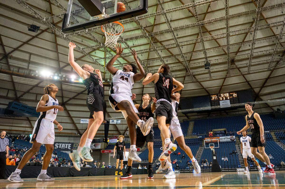 After grabbing his own miss, Rainier Beach forward Josh Conerly Jr. (44) attempts another shot underneath the basket as Ferris forward Alec Roland (15) and guard Dylan Skaife (14) defend during the third quarter of a Class 3A state tournament game on Wednesday, March 2, 2022, at the Tacoma Dome, in Tacoma, Wash.