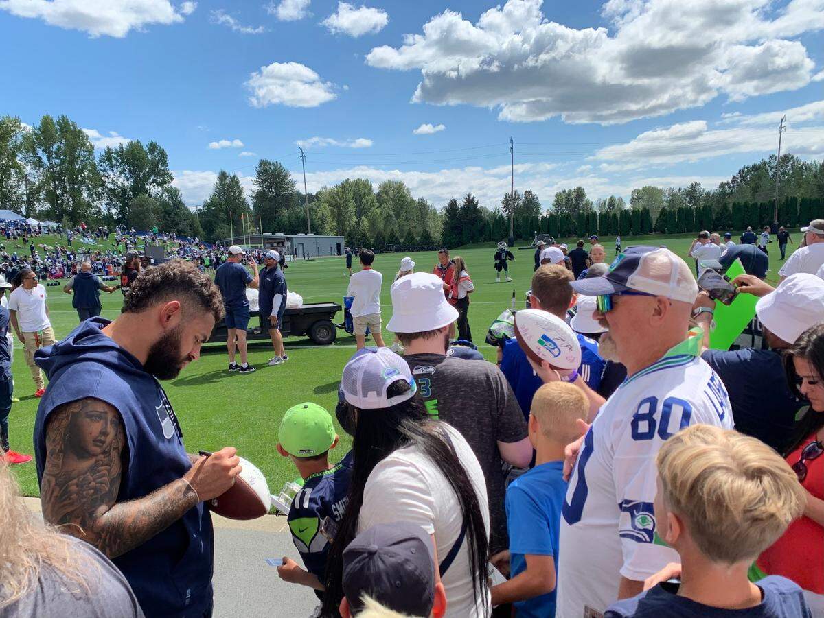 Starting right tackle Abe Lucas (left) signs autographs for fans after the first practice of Seahawks training camp at the Virginia Mason Athletic Center in Renton July 24, 2024. Lucas remained sidelined following offseason surgery on his knee.