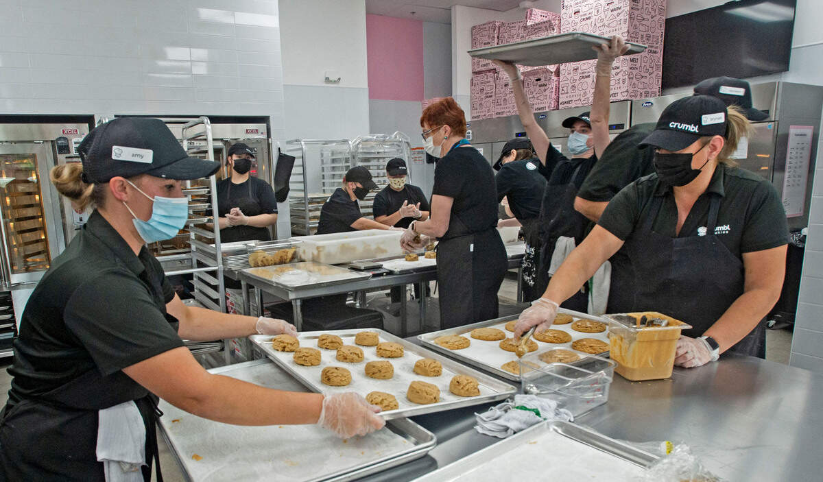 As co-owner Amy Beam, left, and manager Brynan Heim prep a tray of Reese’s peanut butter cookies, a team of employees bustle behind them during the soft launch of the cookie franchise Crumbl at 4784 Borgen Blvd in the Costco complex on Thursday, Oct. 21, 2021.