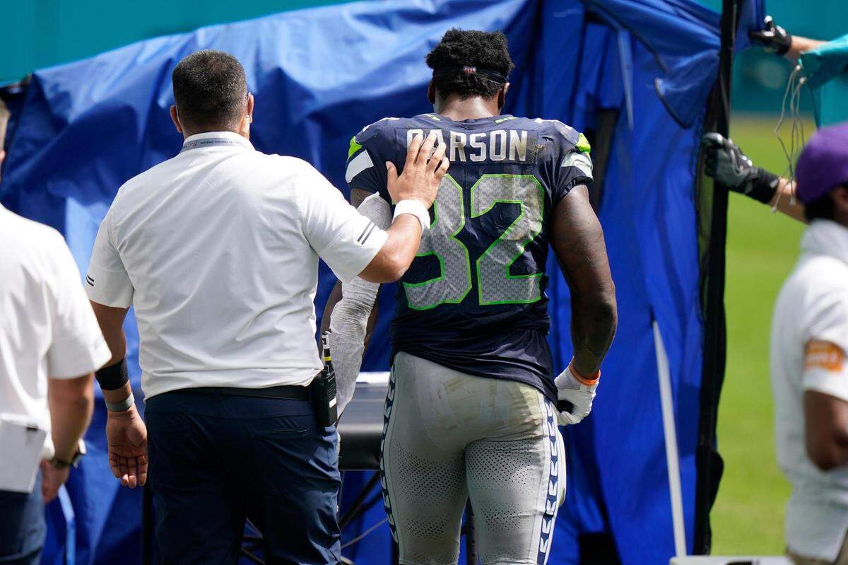 Seattle Seahawks running back Chris Carson (32) is taken off the field, during the first half of an NFL football game against the Miami Dolphins, Sunday, Oct. 4, 2020 in Miami Gardens, Fla. (AP Photo/Wilfredo Lee)