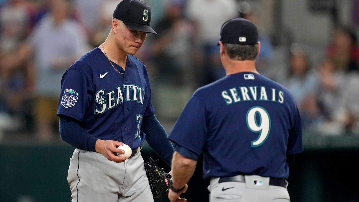 Seattle Mariners starting pitcher Bryan Woo, left, turns the ball over to manager Scott Servais (9) in the fourth inning of a baseball game against the Texas Rangers, Sunday, Sept. 24, 2023, in Arlington, Texas. Woo earned his major league all-star selection this year. (AP Photo/Tony Gutierrez)