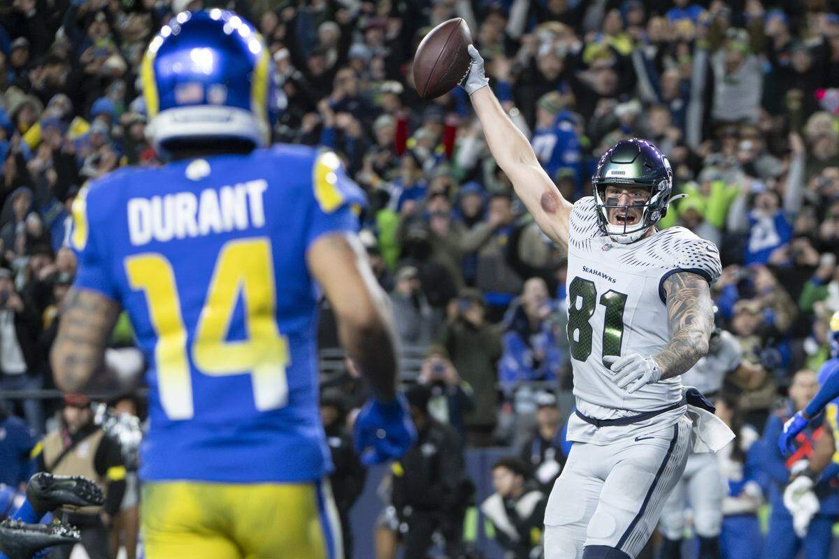 Seattle Seahawks tight end Eric Saubert (81) raises the ball in celebration of his two point conversion, winning the game against the Los Angeles Rams in overtime at Lumen Field, on Thursday, Dec. 18, 2025, in Seattle.
