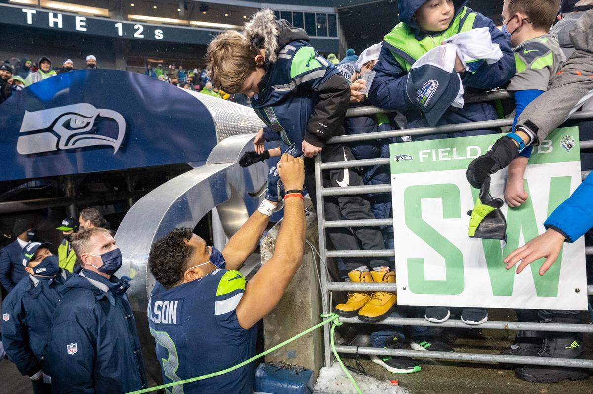 Seattle quarterback Russell Wilson (3) signs a young boys jersey as he leaves Lumen Field after leading the Seahawks to a 51-29 win over the Detroit Lions on Sunday, Jan. 2, 2022, in Seattle.