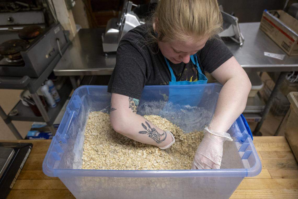 Emily Sherwood, an employee at Antique Sandwich Co., hand mixes a batch of granola in the kitchen on Tuesday, April 14, 2026, in Tacoma.