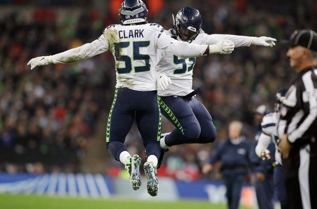 Frank Clark (55) celebrates with fellow defensive end Branden Jackson (93) after one of Clark’s 2 1/2 sacks of Oakland Raiders quarterback Derek Carr (4) Sunday night at Wembley Stadium in London. Clark was a main reason Seattle throttled Oakland’s offense in the 27-3 win.