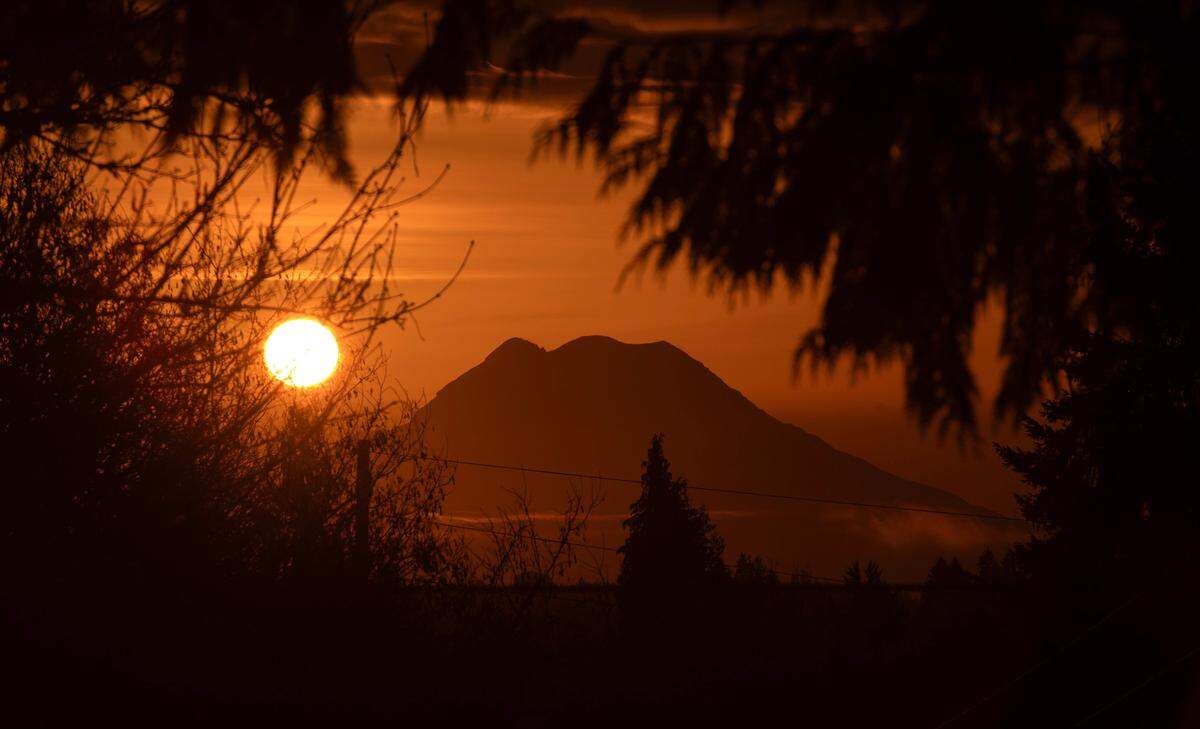 The sun rises behind Mount Rainier as seen from Tumwater, Washington, on March 7, 2024.