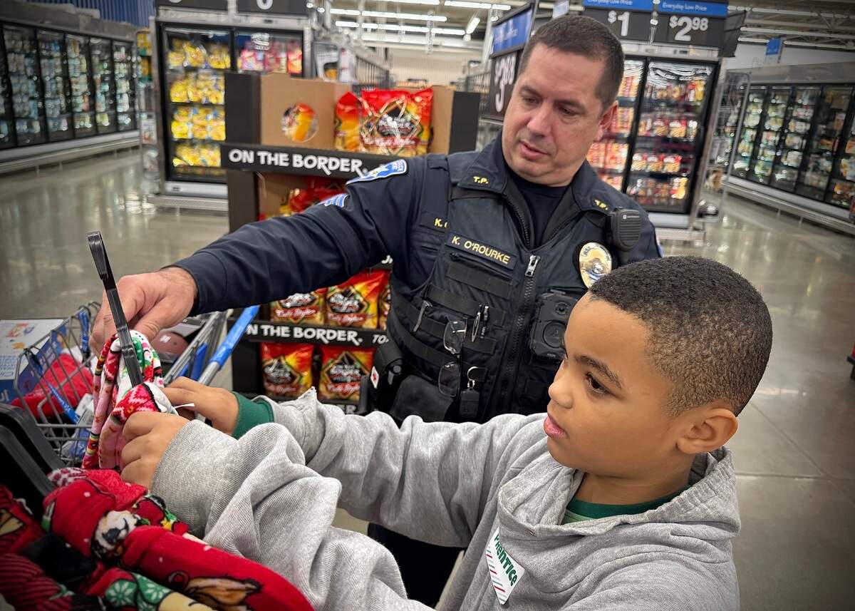 Prentice Barden, 9, gets shopping advice from Tacoma Police Sergeant Keith O’Rourke Saturday, Dec. 14, 2024 during the annual Shop With A Tacoma Cop event at Walmart in Tacoma.